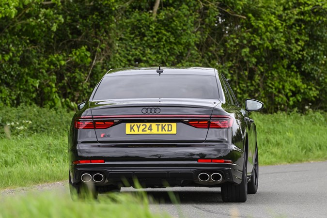 Image of a black Audi S8 driving around a corner, looking at its rear end