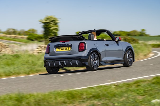 Image of a grey MINI JCW convertible driving round a corner, viewed from the rear