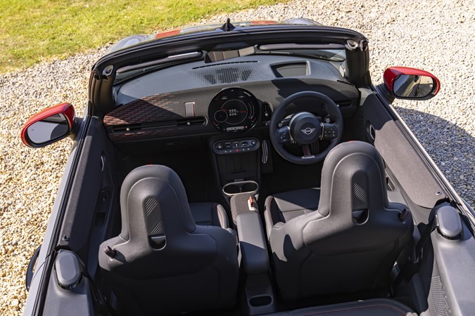 Image of an MINI JCW's convertible interior with the hood folded, looking forward from the rear, from a high view-point