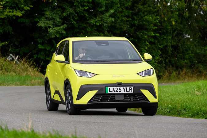 BYD Dolphin Surf (2025) review: front three quarter cornering, yellow paint, grassy B-road