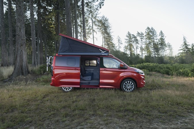 Image of the Ford Transit Custom Nugget parked on grass, seen from the right side, with the pop top raised and side door open