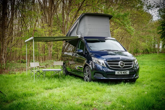 Image of the Mercedes Marco Polo parked on grass, with the pop-top raised and awning out
