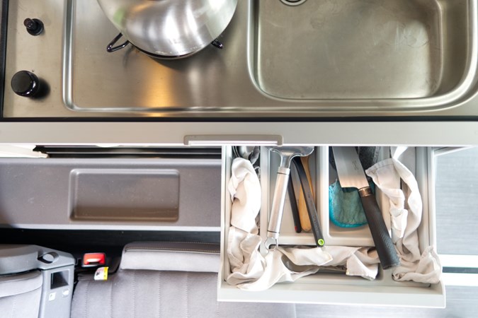 Image of an open campervan cutlery drawer stuffed with hankies to prevent rattles