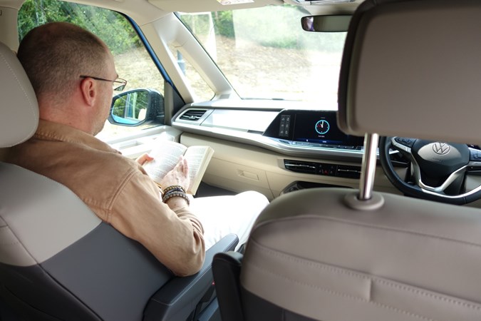 Image of a man reading in the front passenger seat of a campervan