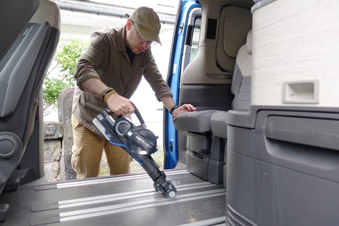 Image of a man vacuuming the floor of a campervan