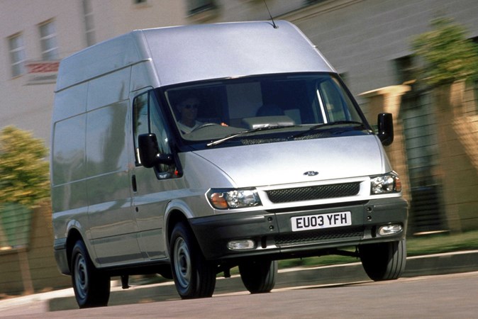 Image of a silver 2003 Ford Transit driving on an urban street, viewed from the front right corner