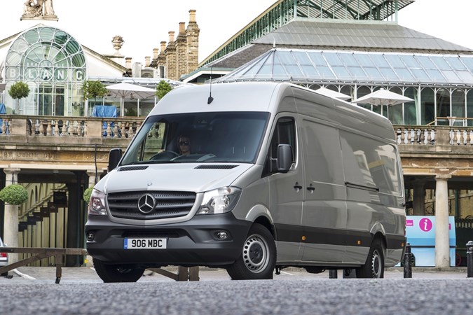 Image of a silver Mercedes Sprinter, static in a city centre, viewed from the front left corner