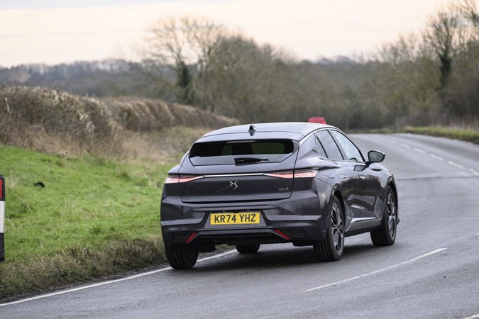 Image of a DS 4, in grey, driving round a right-hand corner, viewed from the car's rear right corner