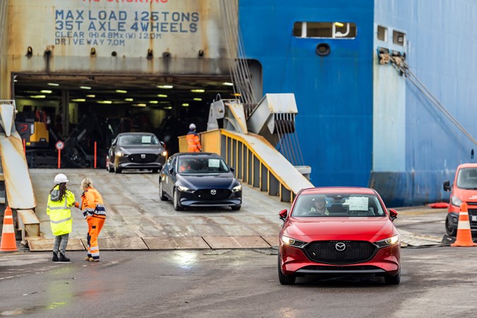 Image of several Mazda cars being driven off a transport ship