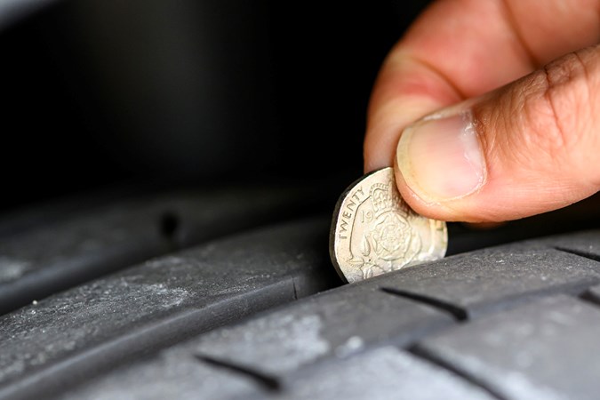 Image of a 20p coin inserted into a tyre's tread to check its depth