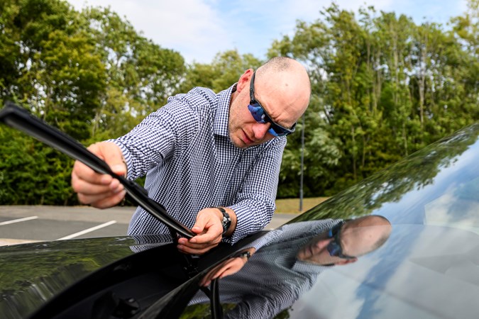 Image of a man checking the condition of a car's wiper blades