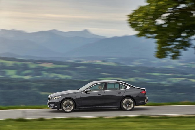 Image of a grey 2024 BMW 530e, viewed from the left side while driving