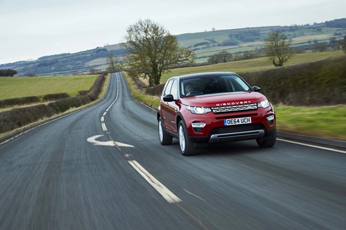 Image of a red Land Rover Discovery Sport. viewed from the front right corner while driving