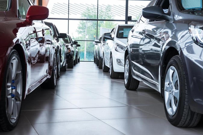 Image of two rows of cars in a showroom, looking between them from a low angle