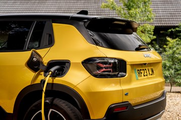A yellow electric hatchback with its plug plugged into a chargepoint